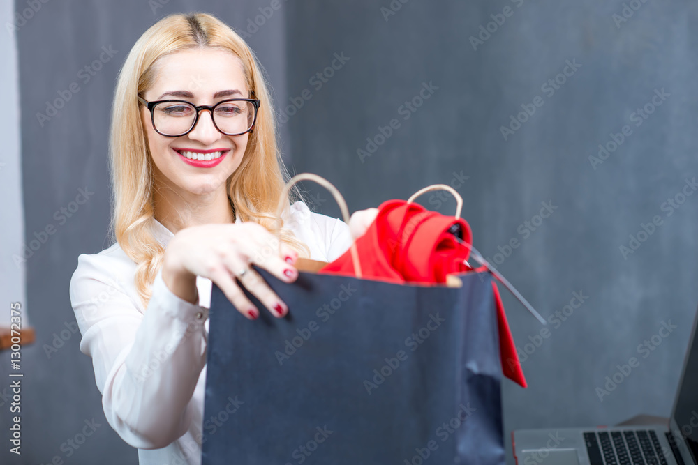 Happy cashier putting clothes into the shopping bag at the paydesk in the clothing store