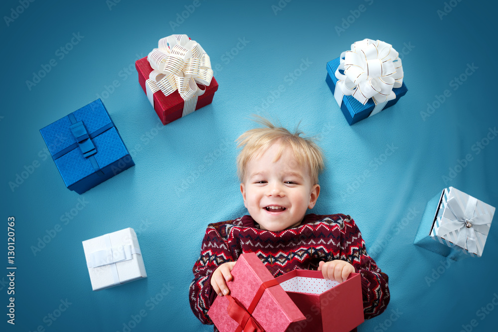 Smiling baby on red blanket with presents