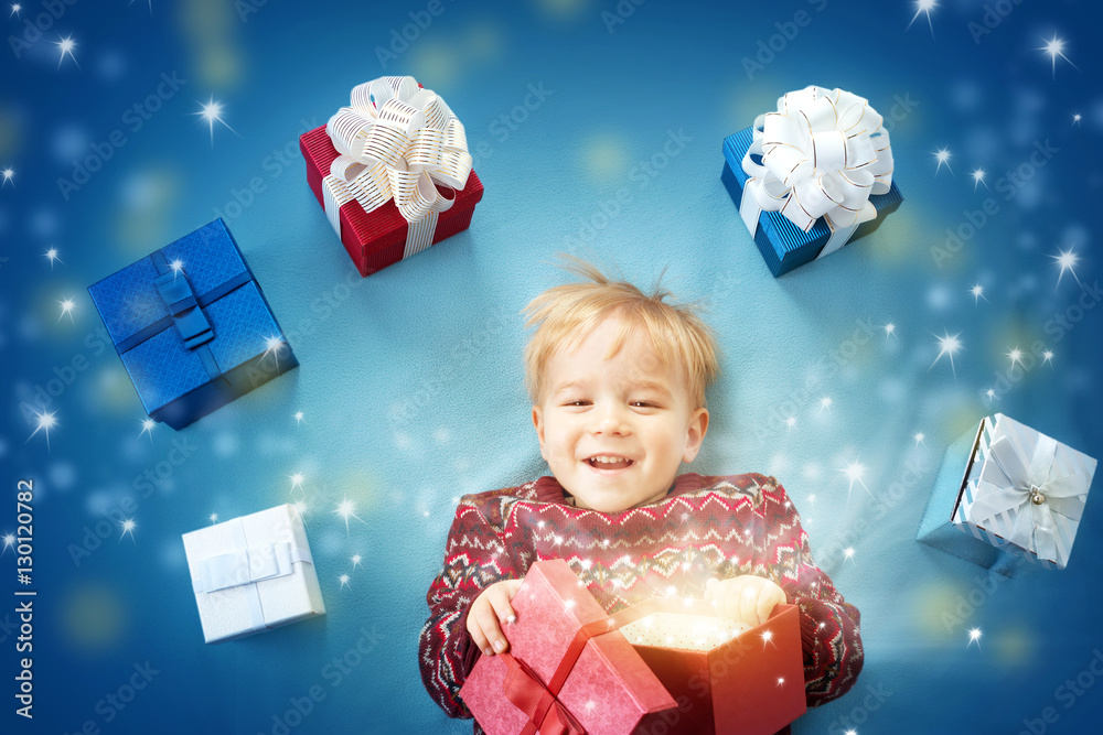 Smiling baby on red blanket with presents