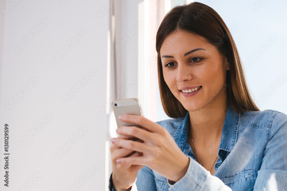 Happy young woman studying at home reading an sms or text messag