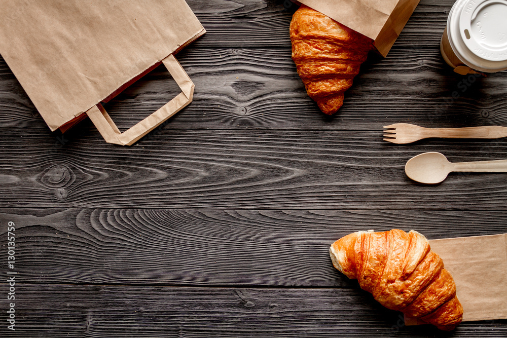 cup coffee and bread in paper bag on wooden background