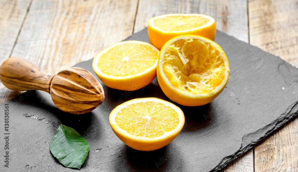 cut oranges in half and juicer on wooden background