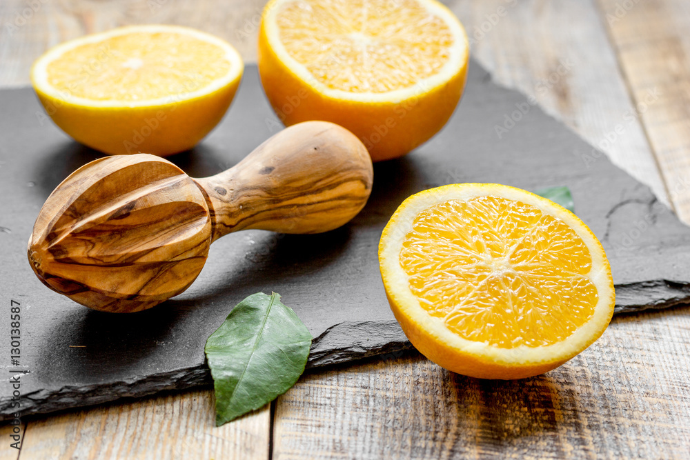 cut oranges in half and juicer on wooden background