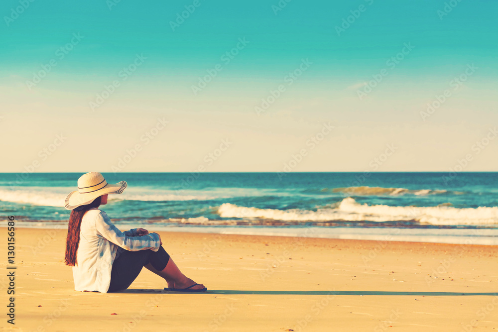 Woman in a hat sitting on the beach