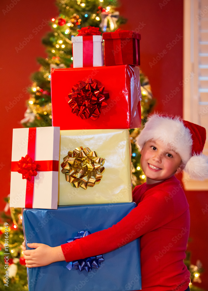 Happy boy holding many Christmas gifts