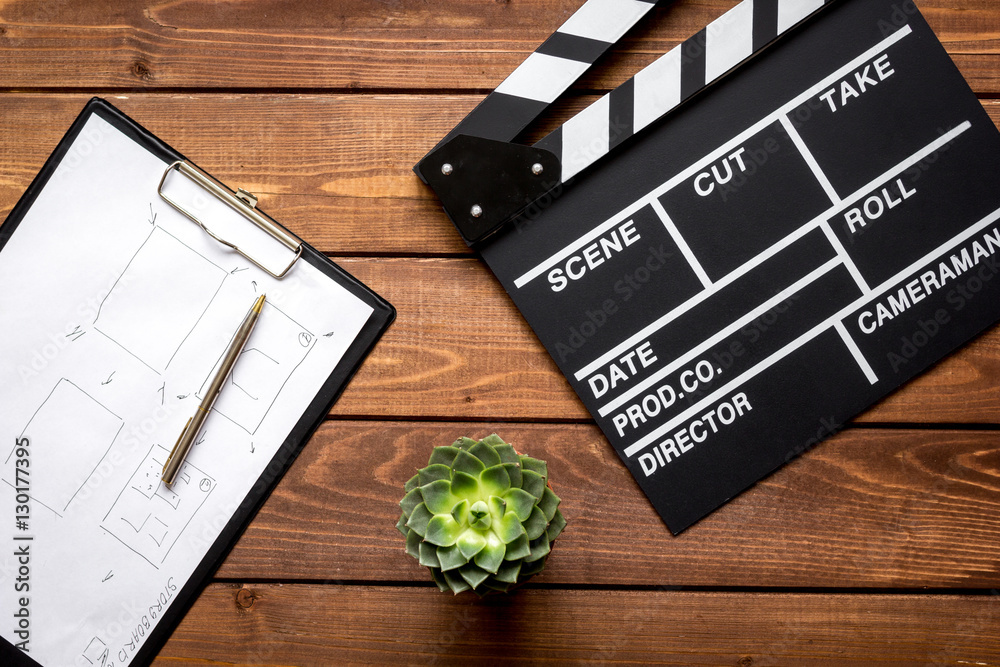 Screenwriter desktop with movie clapper board wooden background top view