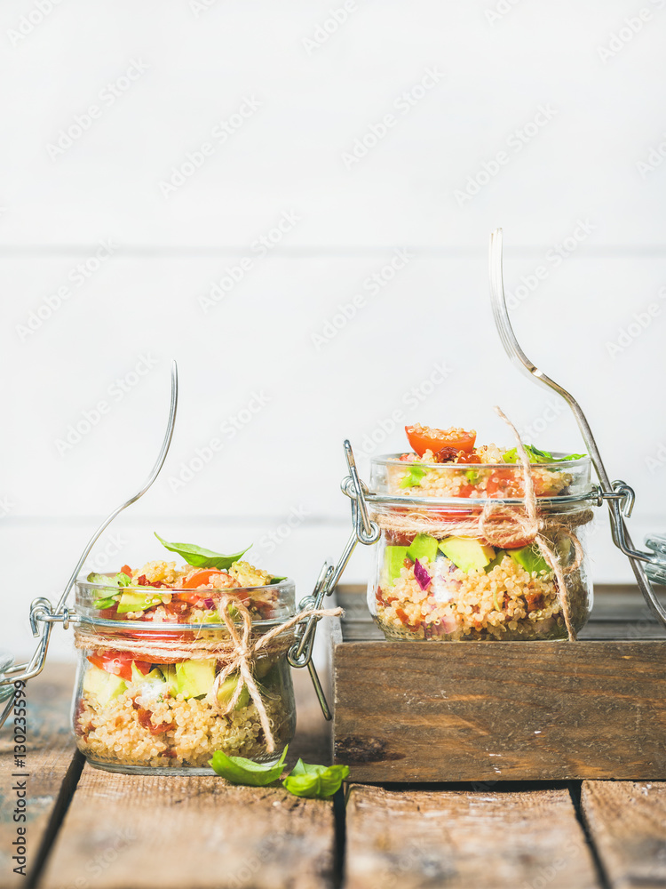 Healthy homemade jar quinoa salad with sun-dried and cherry-tomatoes, avocado and fresh green basil 