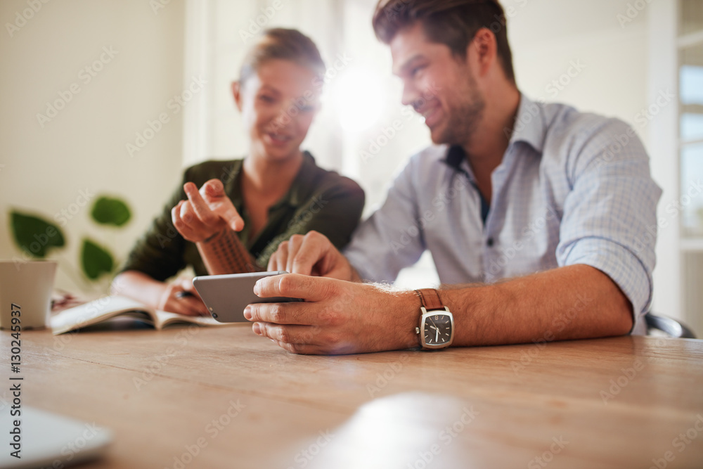 Couple sitting together at table using mobile phone