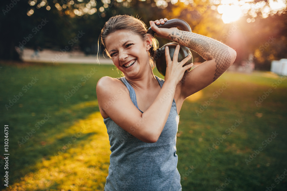 Happy young woman with kettlebell in park