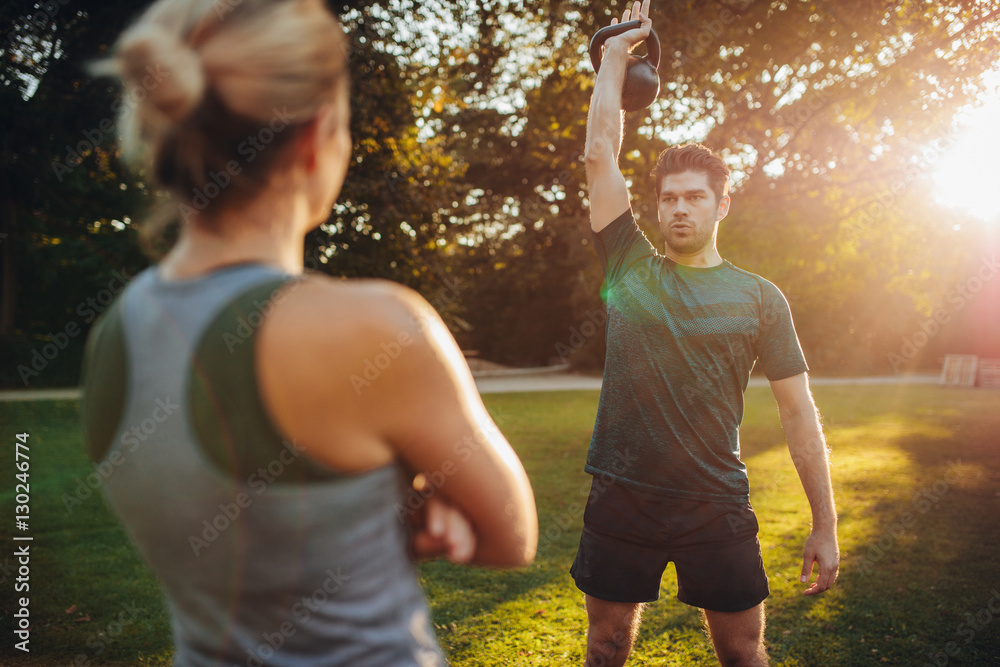 Fit man exercising with female trainer in park