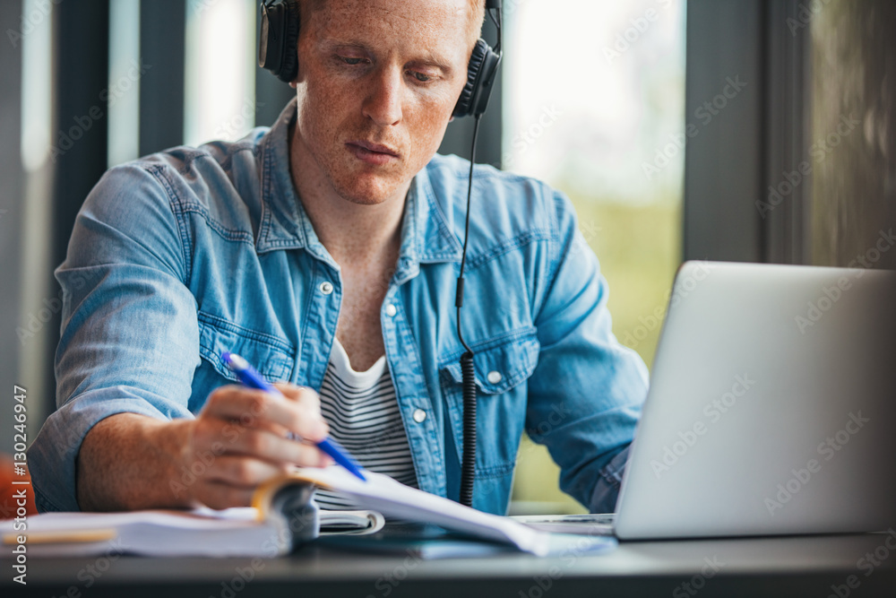 Student with laptop reading book at college library