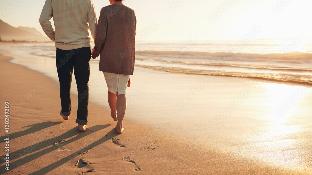 Senior couple holding hands walking on the beach