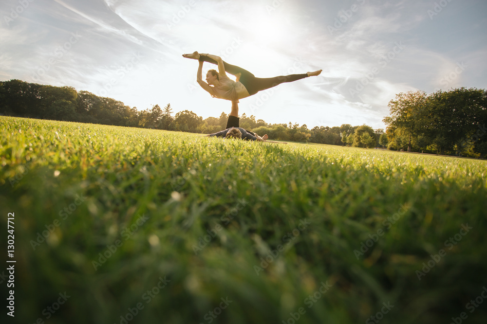 Man and woman in park practising pair yoga