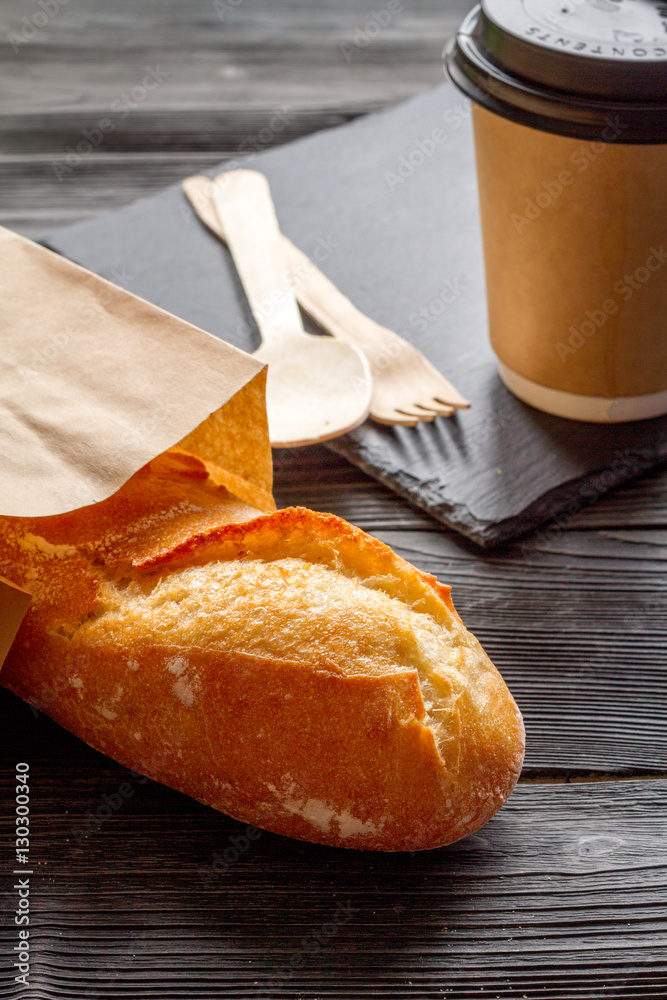 cup coffee and bread in paper bag on wooden background