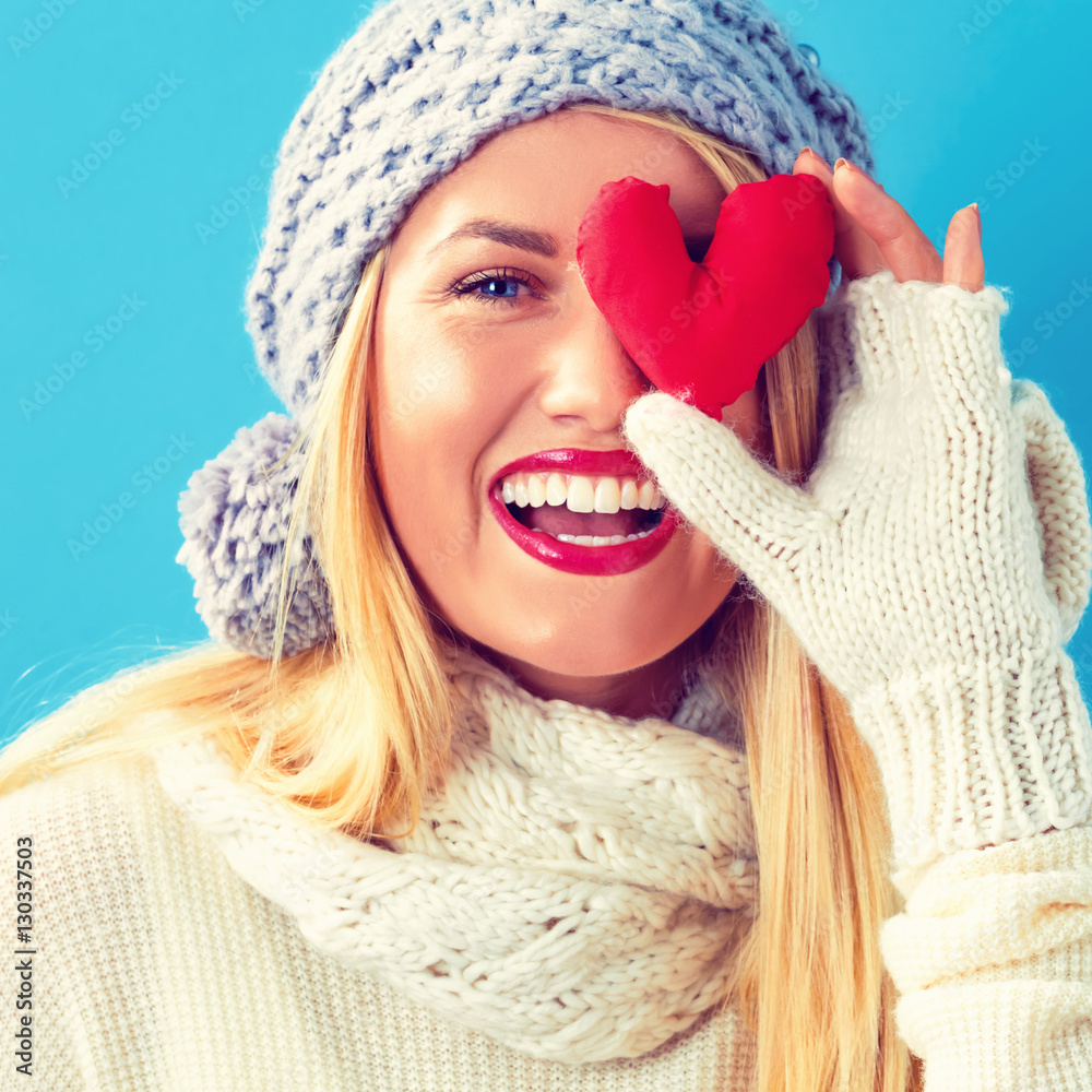 Happy young woman holding a heart cushion