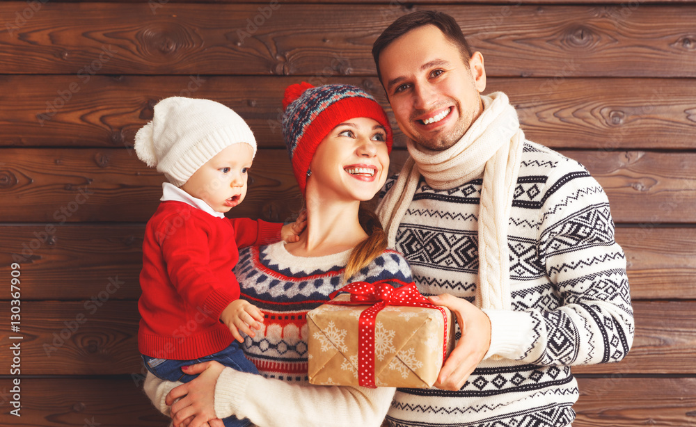 happy family mother, father and baby with Christmas gifts on woo