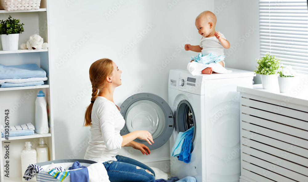 mother housewife with baby engaged in laundry fold clothes into