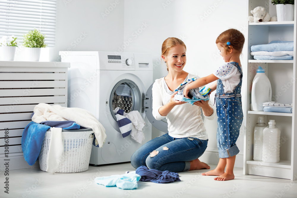 family mother and child girl  in laundry room near washing machi