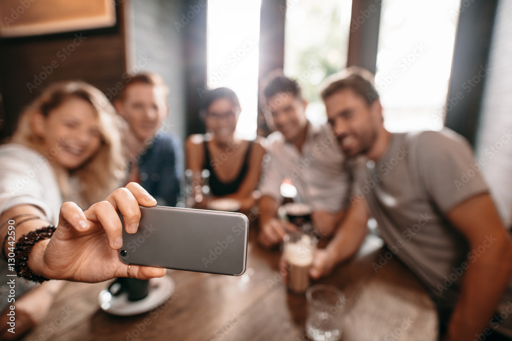 Group of young people taking a selfie at cafe