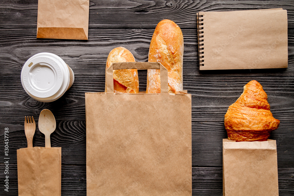 cup coffee and bread in paper bag on wooden background