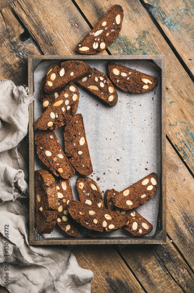 Dark chocolate and sea salt Biscotti with almonds in wooden tray over rustic wooden background, top 