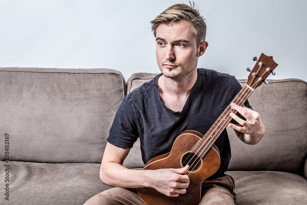 handsome man playing ukulele or small guitar with worry feeling