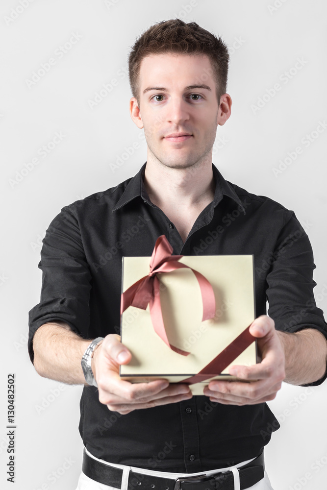 Handsome businessman holding gift box over light gray background