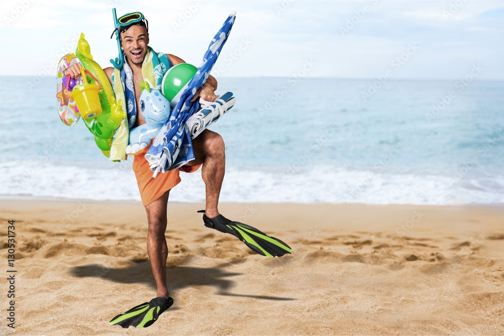 Smiling man holding is beach equipment.