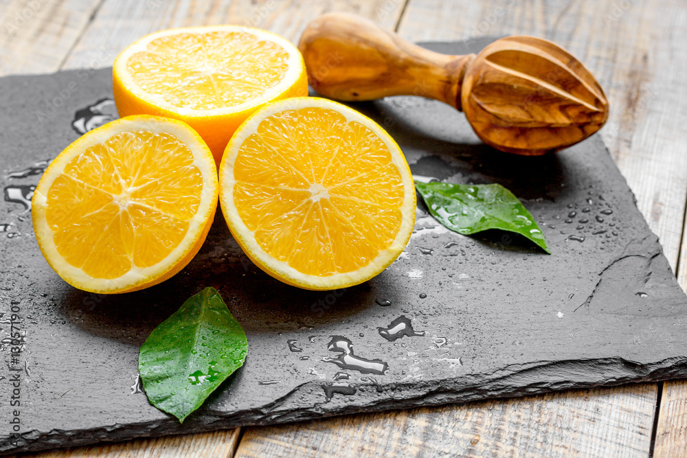 cut oranges in half and juicer on wooden background