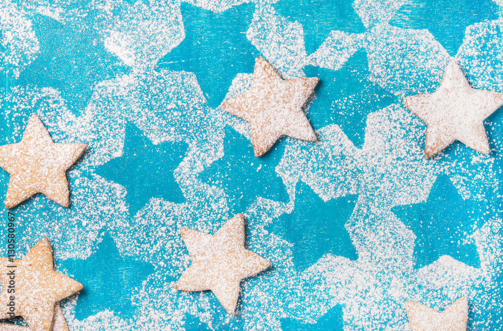 Heart shaped cookies with sugar powder over bright blue background, top view, horizontal composition