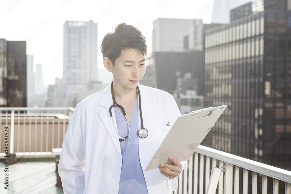 A handsome male doctor is looking at the chart on the roof