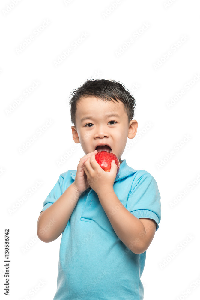 Asian baby boy holding and eating red apple, isolated on white