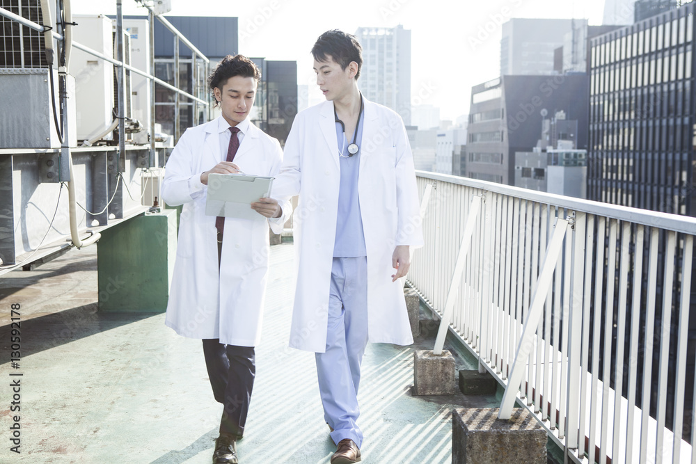 Two doctors are talking on the roof while watching the medical record