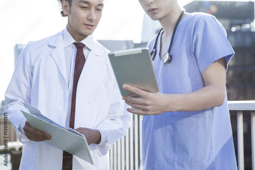 Two young doctors are watching electronic tablet on the hospitals rooftop