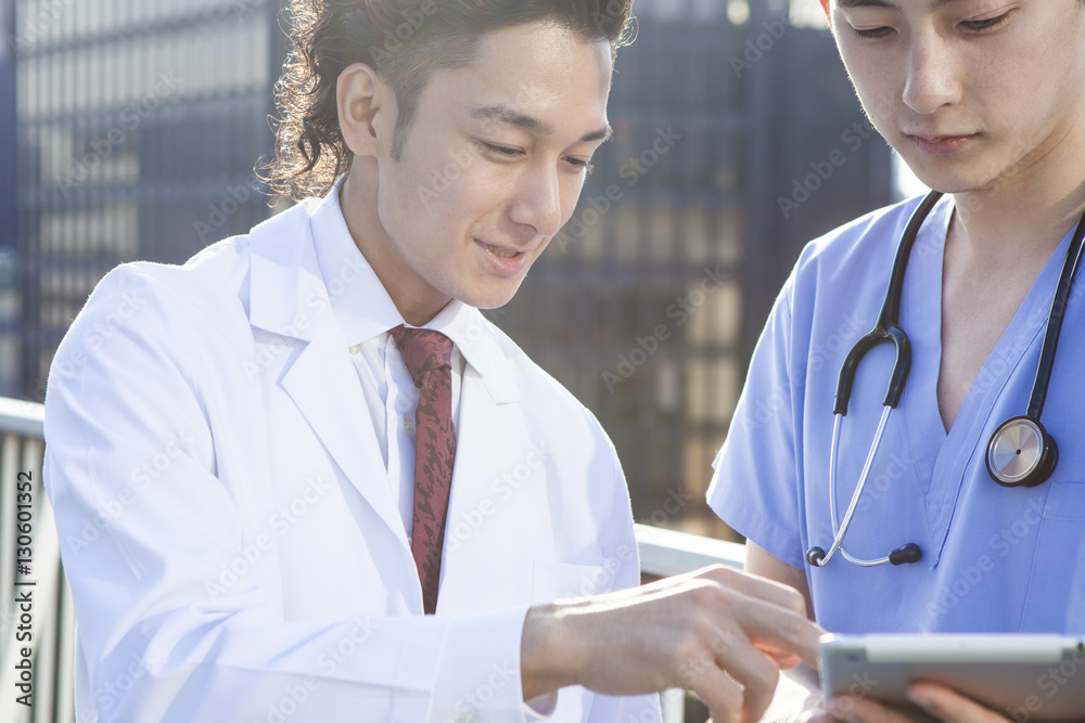 Two young doctors are watching electronic tablet on the hospitals rooftop