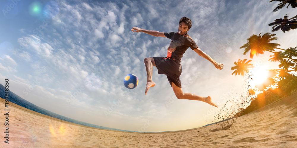 Beach soccer player in action. Sunny beach wide angle and sea