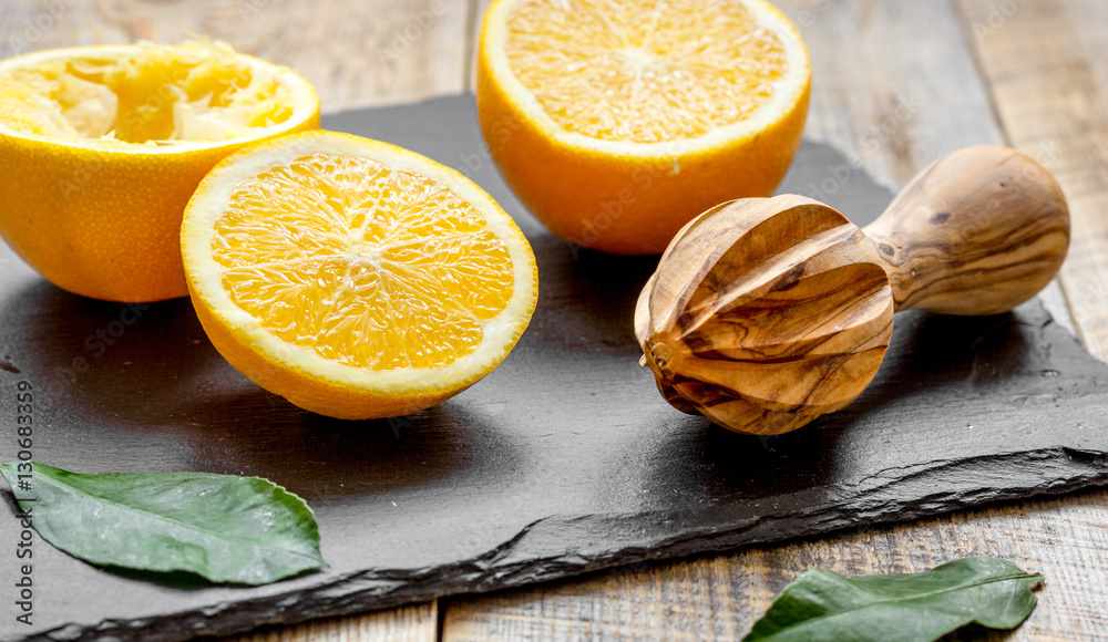 cut oranges in half and juicer on wooden background