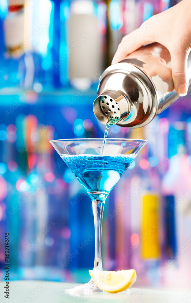 Hand of barman pouring liqueur to cocktail glass