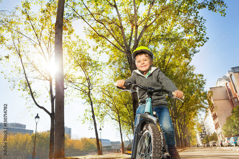 Portrait of happy boy riding his bike at city park