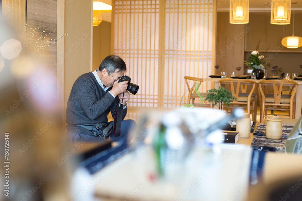 old asian man takes photo in modern living room