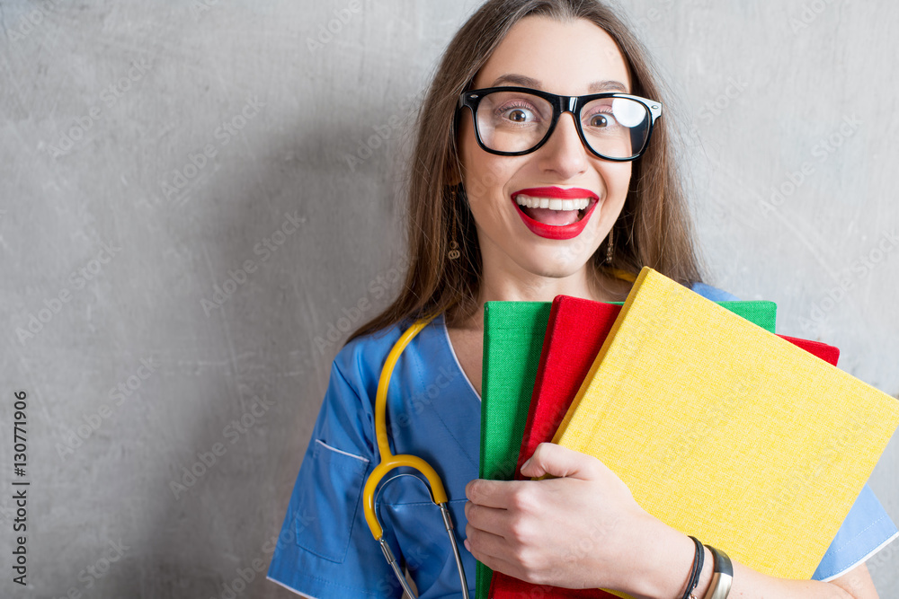 Portrait of a young nurse in uniform with stethoscope on the gray wall background