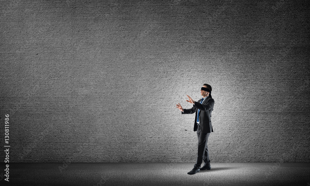 Business concept of risk with businessman wearing blindfold in empty concrete room