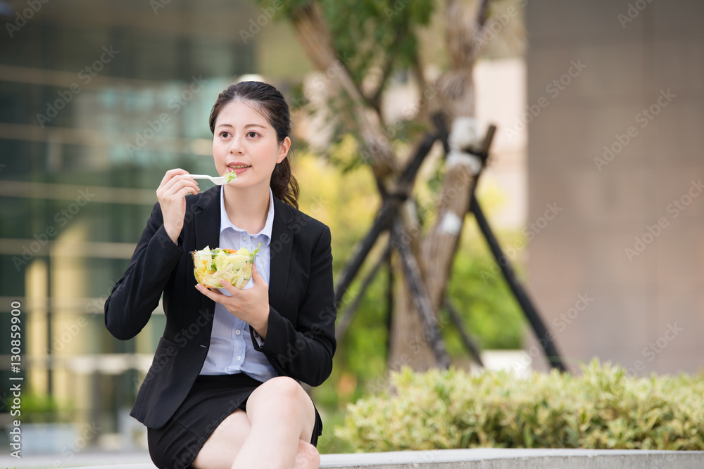 beautiful asian business woman eating salad on park bench