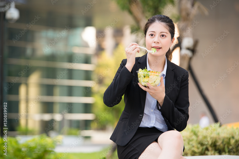 beautiful asian business woman eating salad on park bench