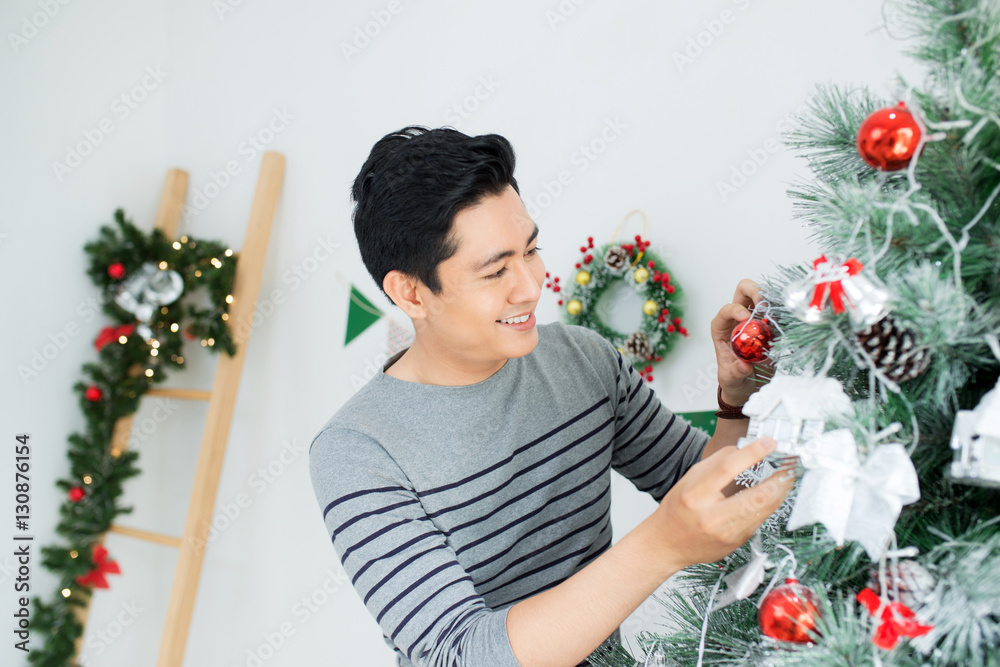 Christmas. Asian Handsome Man standing new Xmas tree at home cel