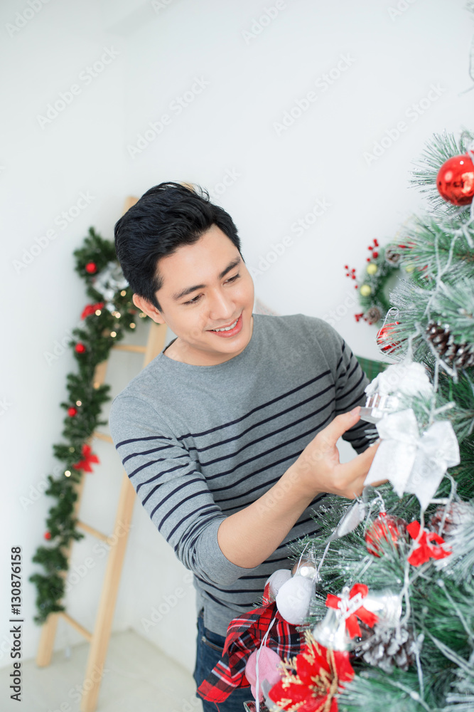 Christmas. Asian Handsome Man standing new Xmas tree at home cel