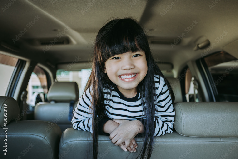 Portrait happy, smiling kid sitting in the car looking out windows, ready for vacation trip