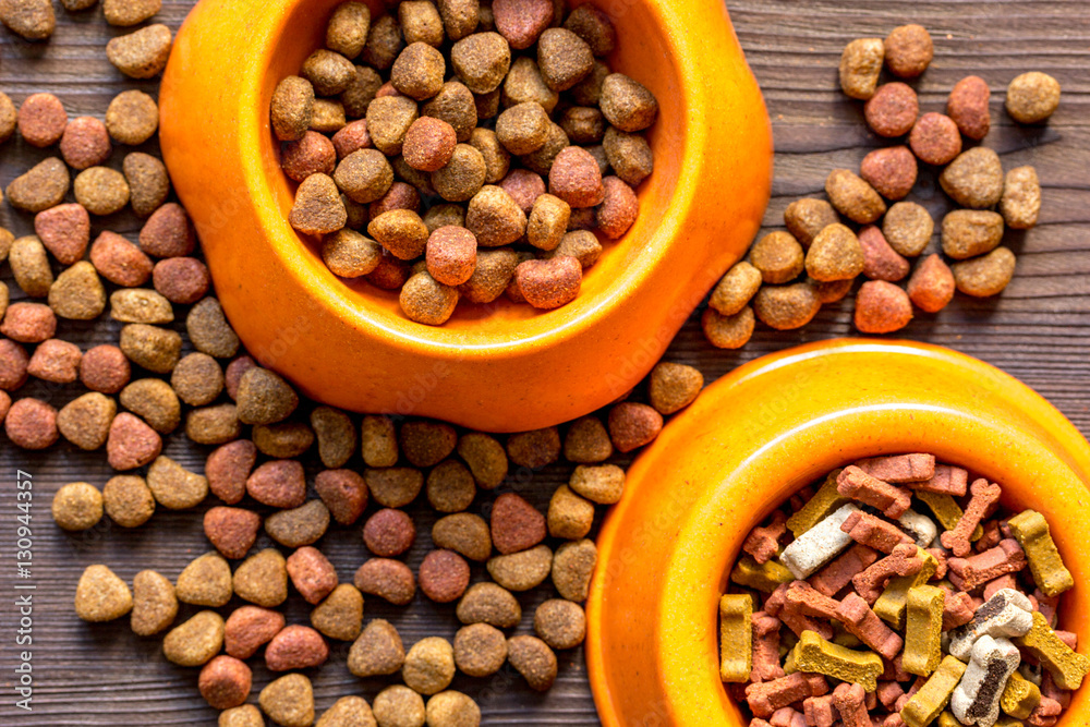 dry dog food in bowl on wooden background top view