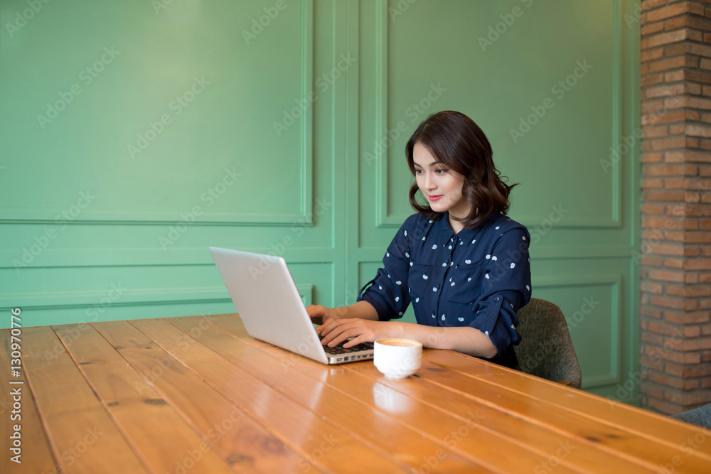 Beautiful cute asian young businesswoman in the cafe, using lapt