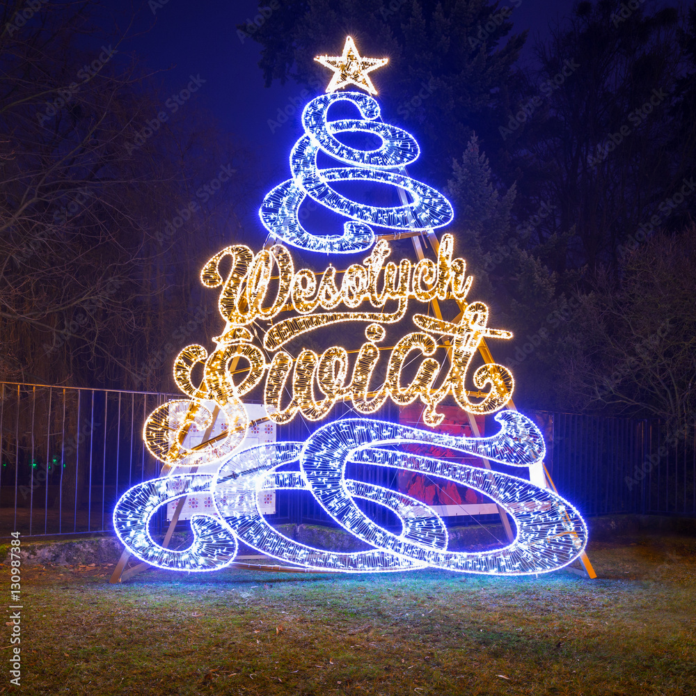 Beautiful Christmas tree illumination at the park with Wesolych Swiat (Polish: Merry Christmas) sign